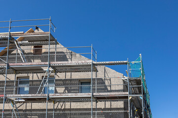 Bauger&uuml;st vor einem Haus, bei dem das Dach erneuert wird.