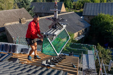 Ein Dach wird neu gedeckt. Unterkonstruktion mit Weichfaserplatten, Dachlatten, Beton-Dachsteine in der Farbe Anthrazit, Dachziegel, Ortgang