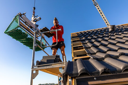 Ein Dach wird neu gedeckt. Unterkonstruktion mit Weichfaserplatten, Dachlatten, Beton-Dachsteine in der Farbe Anthrazit, Dachziegel, Ortgang
