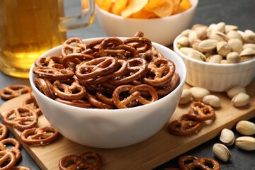 Delicious pretzel crackers, beer and other snacks on black table, closeup
