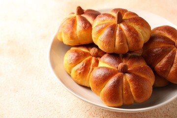 Tasty pumpkin shaped buns on beige textured table, closeup