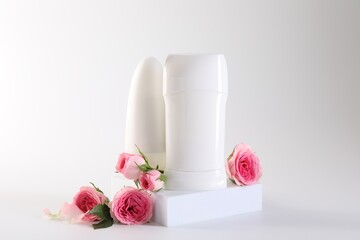 Different deodorants and beautiful rose flowers on white background