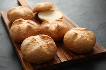 Board with homemade tasty buns on black textured table, closeup