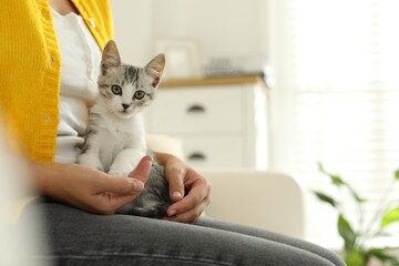 Woman with cute kitten at home, closeup. Space for text