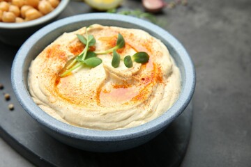 Delicious hummus with paprika served on dark grey table