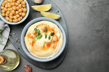 Delicious hummus with paprika and chickpeas served on dark grey table, flat lay. Space for text