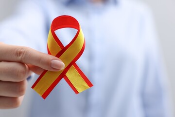 Woman with yellow and red ribbon on grey background, closeup with space for text. Hepatitis C...