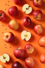 Fresh red apples and seeds on orange background, flat lay