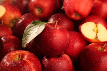 Fresh ripe red apples and green leaf as background, closeup