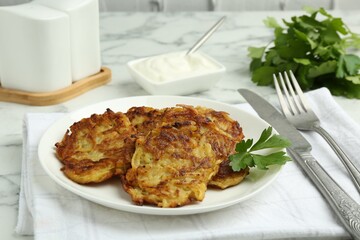 Delicious potato pancakes served on white marble table, closeup