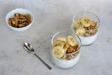 two glasses of chia pudding with cereal, bananas and walnut 