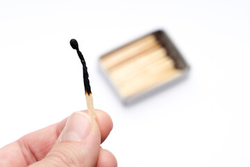 Hand holding burnt match stick on white background