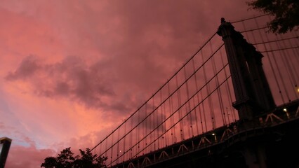 Manhattan Bridge to Brooklyn Dumbo. New York City symbol, USA travel destination. Architecture of United States of America, tourist landmark. Cables, evening sunset dramatic cloudy pink rainy sky.