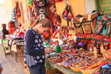 preteen girl  in a looking at goods at street market in village of Purmamarca, Jujuy, Argentina
