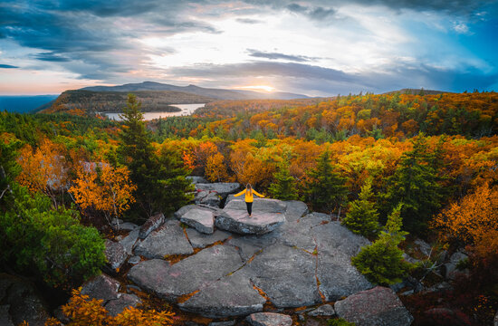 Epic Outdoor Freedom Inspiring Wide View on Female Hiker Adventure Travel Yellow Coat On Mountain Arms Up Autumn Colorful Forest Catskills New York - Powered by Adobe