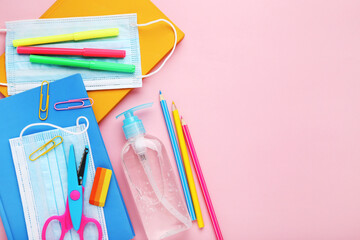 Fototapeta premium Medicine masks with sanitizer bottle and school stationery on pink background