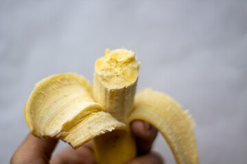 A person holds a banana that has been bitten.