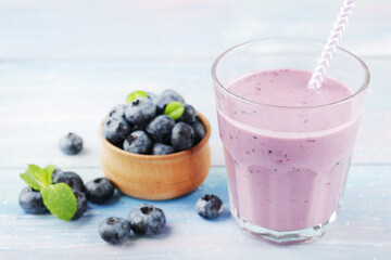 Blueberry in bowl with smoothie and mint leafs on blue wooden background