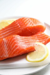 Pieces of fresh salmon with lemon on white table, closeup