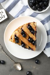 Slice of delicious homemade blueberry pie served on grey table, flat lay