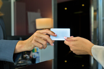 Close-up of hotel keycard exchange between two people at reception desk.