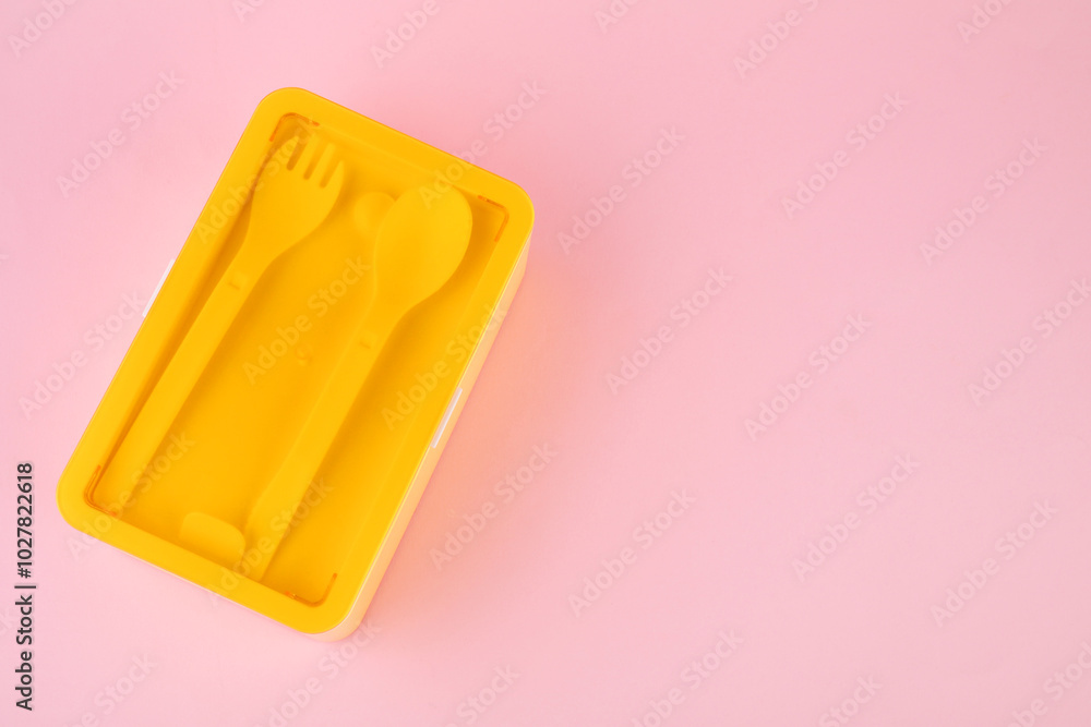 Wall mural Plastic lunch box with cutlery on light pink background, top view. Space for text