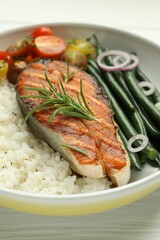 Tasty grilled salmon steak with rice and vegetables on white wooden table, closeup