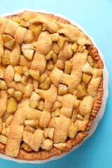 Tasty homemade apple pie on light blue background, top view
