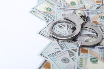 Corruption concept. Handcuffs and dollar banknotes on white background, closeup. Space for text