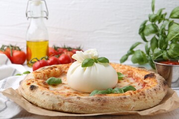 Delicious pizza with burrata cheese, basil, sauce and tomatoes on table, closeup