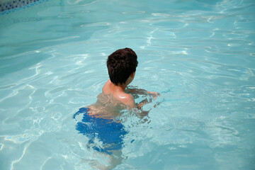 Child swimming in swimming pool. Summer vacation.