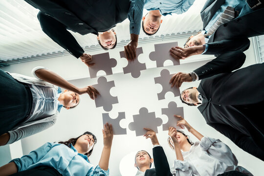 Multiethnic business people holding jigsaw pieces and merge them together as effective solution solving teamwork, shared vision and common goal combining diverse talent. Below view. Habiliment
