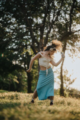 A gorgeous girl performs modern dance in a sunlit park, expressing freedom and joy. Her movements capture the essence of summer and the beauty of outdoor dance practice.