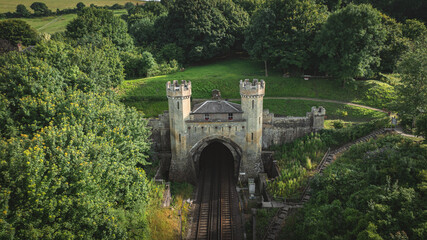 Fototapeta premium Rail track tunnel with castle looking house on top, in a green hill, East Sussex, UK