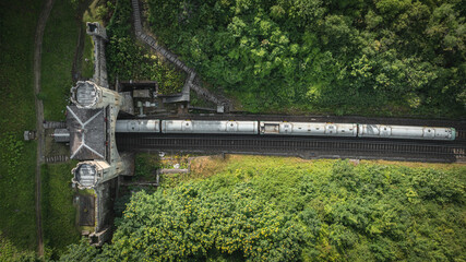 Rail track tunnel with castle looking house on top, in a green hill, East Sussex, UK