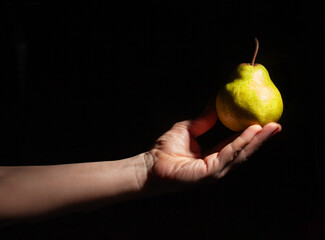 pear in hand on black background