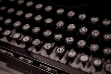 A close-up shot of an old typewriter keyboard with the letters H, J, K, L, N, M, and O visible