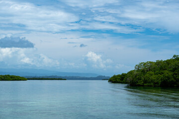 Beautiful island scenery with a bright blue sky, green foliage, and calm waters reflecting the natural beauty of the coastline, environment for travel, summer vacations, peaceful retreats
