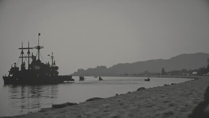 Fototapeta premium Vintage black-and-white photograph of a naval ship near a calm shoreline