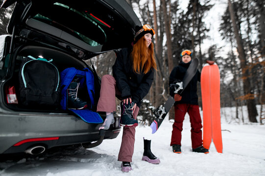 Cute smiling female snowboarder with orange ski goggles wears special snowboarding shoes