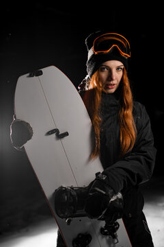 Young pretty snowboarder hugs her splitboard in front of her with two hands