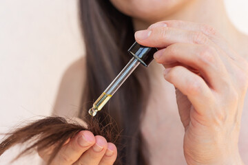 A young pretty woman applying natural oil to her hair against breakage and split ends