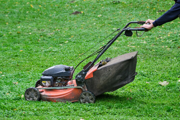 Faceless Person Mowing Grass with a Lawn Mower