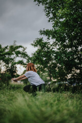 Woman practicing a yoga stretch in a tranquil outdoor environment surrounded by lush greenery, embodying peace and mindfulness.