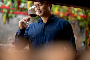 Smiling Man Savoring Wine Aroma in Storage Room – Blurred Wine Bin Creates Focus