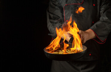 Chef cooking vegetable food on frying pan with rum fire flame. Restaurant and hotel service concept...