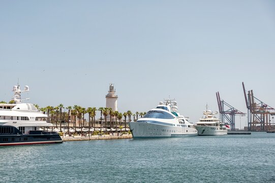 Malaga, Spain; 07-09-2024: Luxury yachts moored in the commercial area known as Muelle Uno in the port of Malaga with views of the city's emblematic maritime lighthouse known as "La Farola"