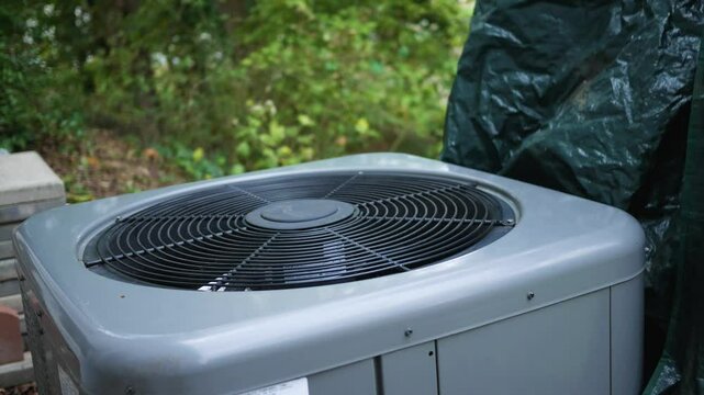 Winterizing series - Man places tarp cover from outdoor air conditioner unit.