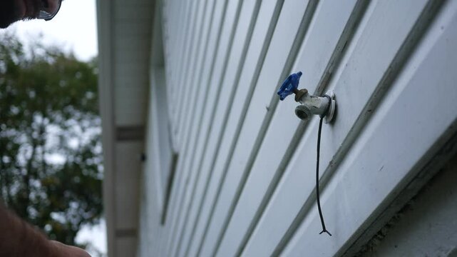 Winterizing series - Man removes hose from spigot and drains water