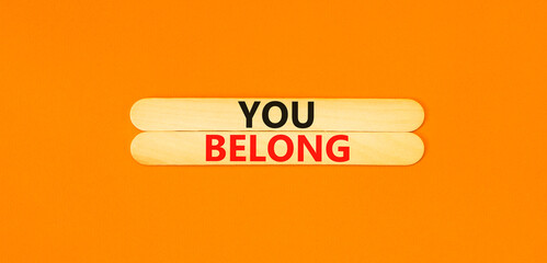 Belonging and you belong symbol. Concept words You belong on beautiful wooden sticks. Beautiful orange background. Business belonging and you belong concept. Copy space.